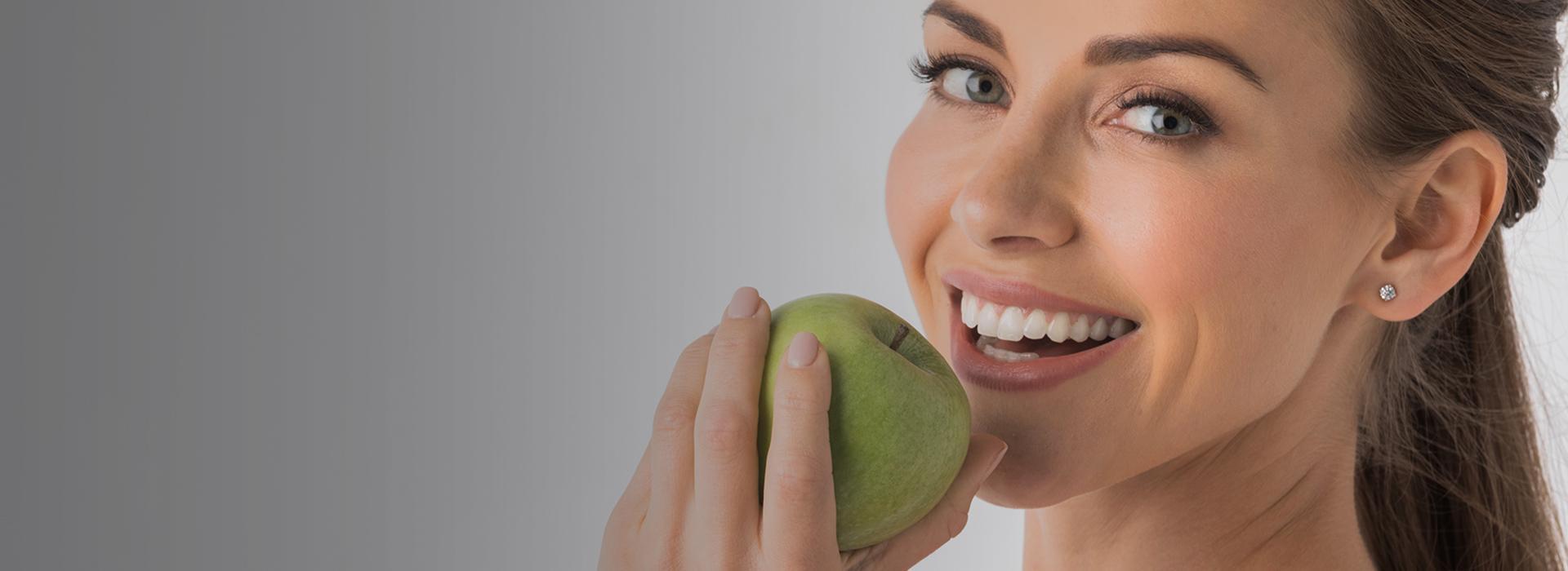 uśmiechnięta kobieta z zielonym jabłkiem